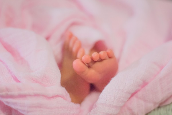 Pieds de bébé enveloppés dans un tissu rose en coton bio, chambre de bébé saine, apaisante et écologique